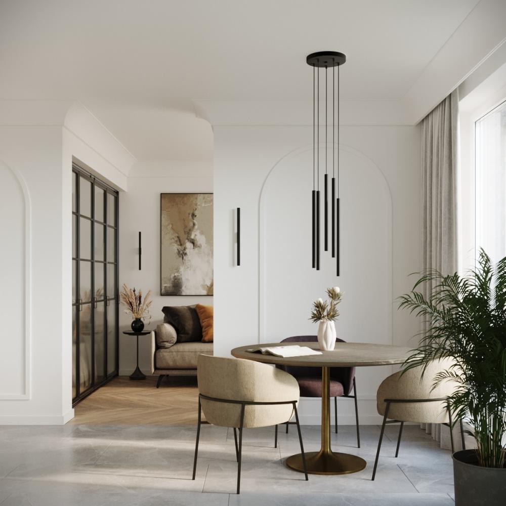 Goudkleurige eettafel en drie kuipstoelen met een minimalistische hanglamp erboven en twee minimalistische wandlampen op de achtergrond