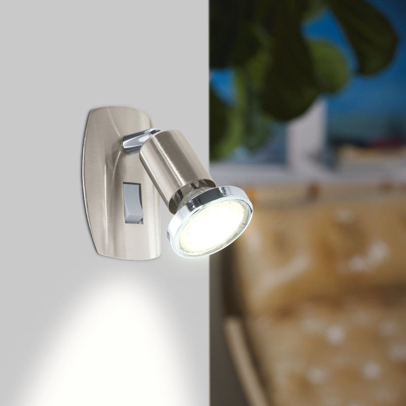 Staalkleurig stekkerlampje met schakelaar en richtbaar spotje met GU10 lampje aan een wand