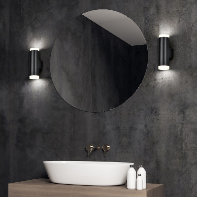 Twee zwarte lampen aan weerszijden van een spiegel boven een wasbak in een badkamer