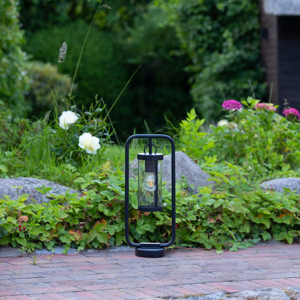 Sokkellamp naast een voetpad in een tuin met groene borders